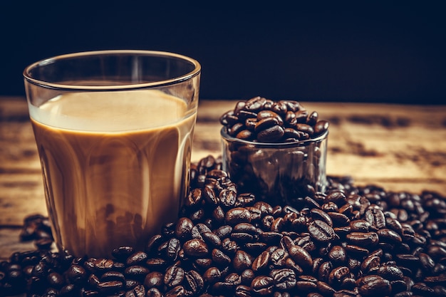 Chicchi di caffè con caffè caldo su legno vecchio