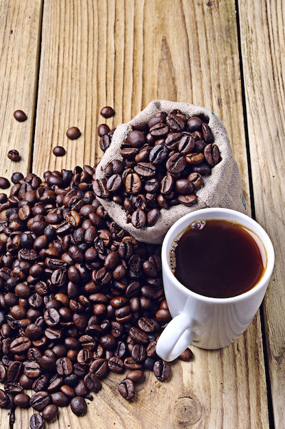 Chicchi di caffè e tazza di caffè su un tavolo di legno