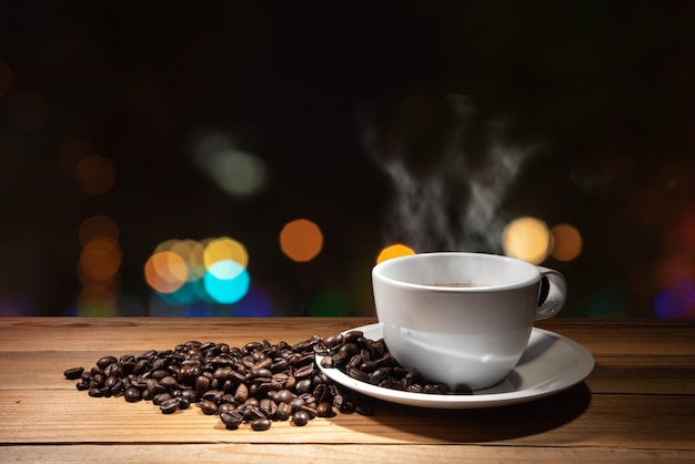 chicchi di caffè e una tazza di caffè caldo sul bokeh di notte