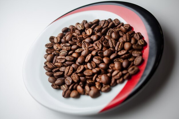 chicchi di caffè fritti in un piattino su uno sfondo bianco Chicchi di caffè come sfondo isolato su bianco