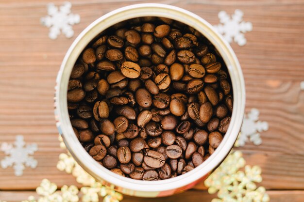 Chicchi di caffè in latta su un tavolo in legno con decorazioni