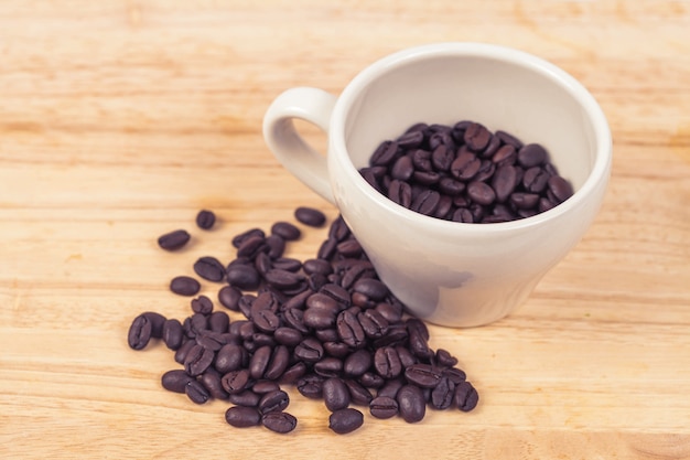 chicchi di caffè in tazza bianca sul tavolo di legno