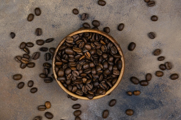 Chicchi di caffè in una ciotola di legno su sfondo scuro