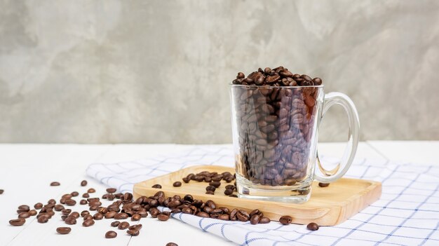 Chicchi di caffè in una tazza su un tavolo di legno.