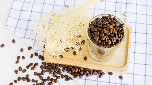 Chicchi di caffè in una tazza su un tavolo di legno.