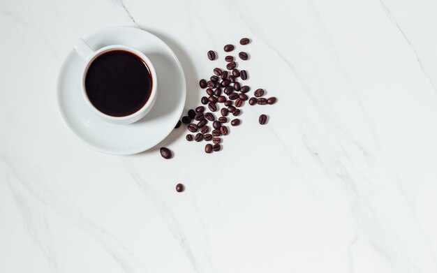 Chicchi di caffè sparsi e tazza di caffè espresso sullo sfondo di marmo