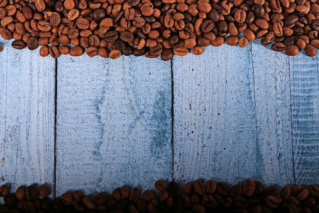 Chicchi di caffè su fondo di legno blu con lo spazio della copia per testo