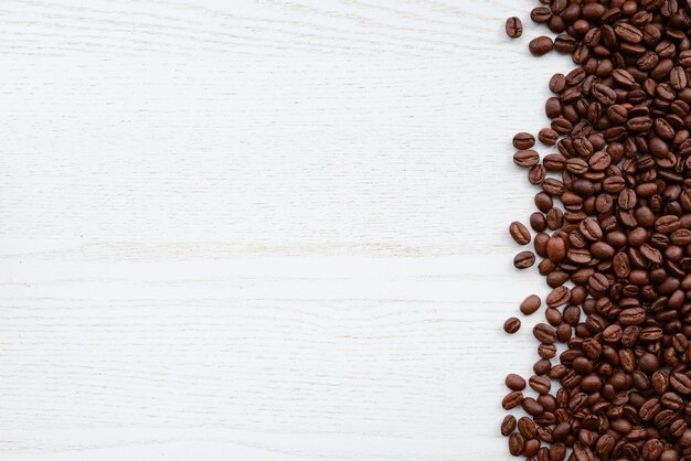 Chicchi di caffè su un tavolo di legno bianco Chicchi di caffè tostati su uno sfondo di legno bianco vista dall'alto