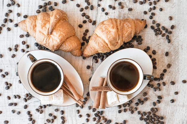 Chicchi di caffè sulla tavola di legno con dolci e croissant