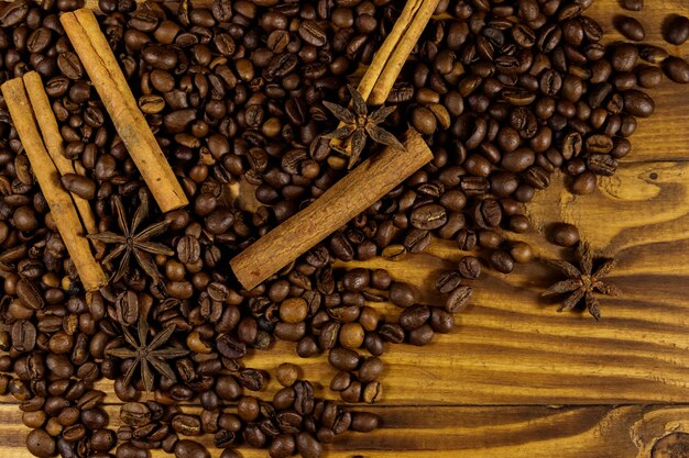 Chicchi di caffè tostati, bastoncini di cannella e anice stellato su fondo di legno rustico. Vista dall'alto