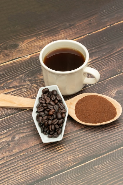 Chicchi di caffè tostati, caffè macinato, tazza di caffè, cucchiaio di legno con caffè tostato