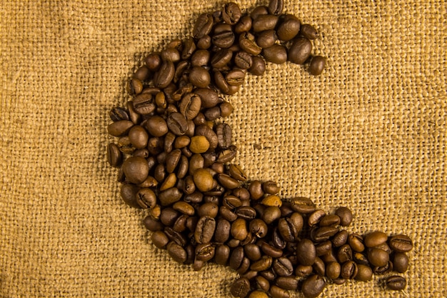 Chicchi di caffè tostati disposti a forma di luna su uno sfondo di tela di sacco