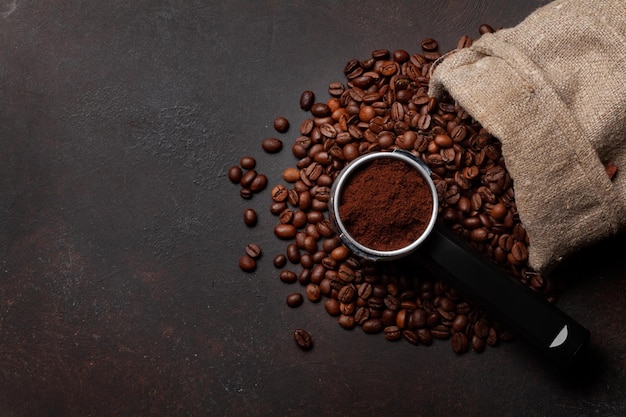 Chicchi di caffè tostati e caffè macinato nel portafiltro