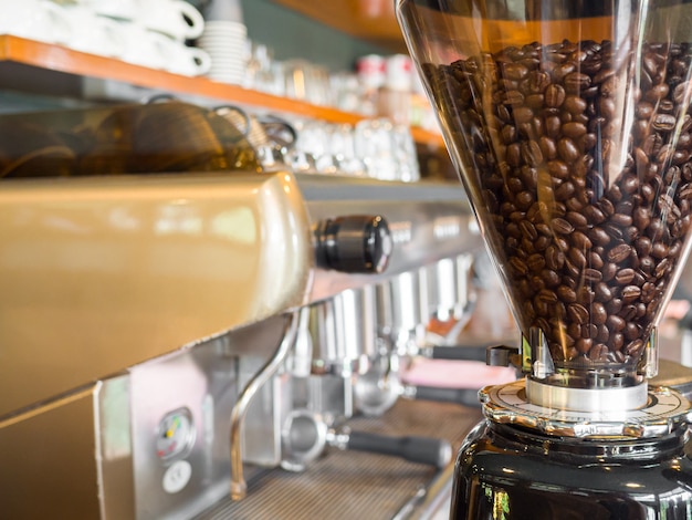 Chicchi di caffè tostati nel macinacaffè elettrico per il processo di preparazione e servire il caffè.