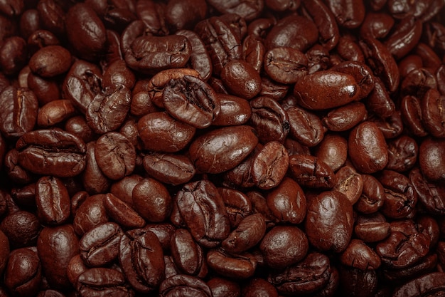 Chicchi di caffè tostati per il caffè in sottofondo da vicino