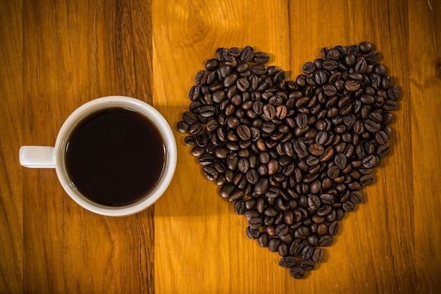 chicchi di caffè tostati sulla tavola di legno con la tazza