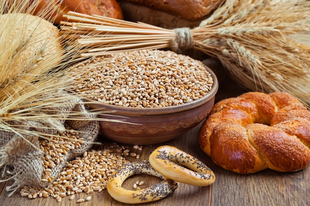 Chicchi di grano e pane su un fondo di legno