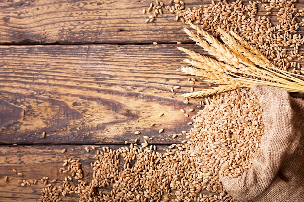 Chicchi di grano in sacco sulla tavola di legno