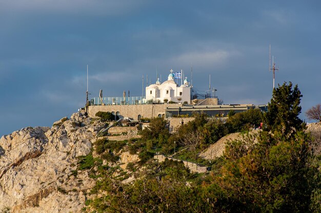 Chiesa ateniese di San Giorgio sul Licabetto contro un paesaggio urbano drammatico del cielo