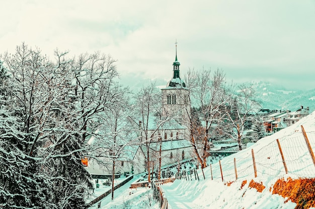 Chiesa con le montagne alpine del villaggio della città di Gruyères in Svizzera nell'inverno