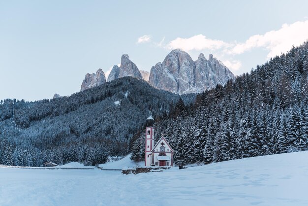 Chiesa in mezzo alle alpi con montagne innevate sullo sfondo