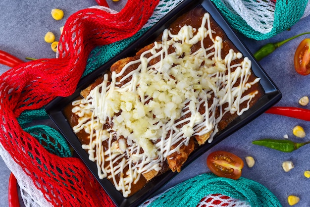 Chilaquiles con pollo e panna acida e salsa con bandiera messicana su sfondo grigio