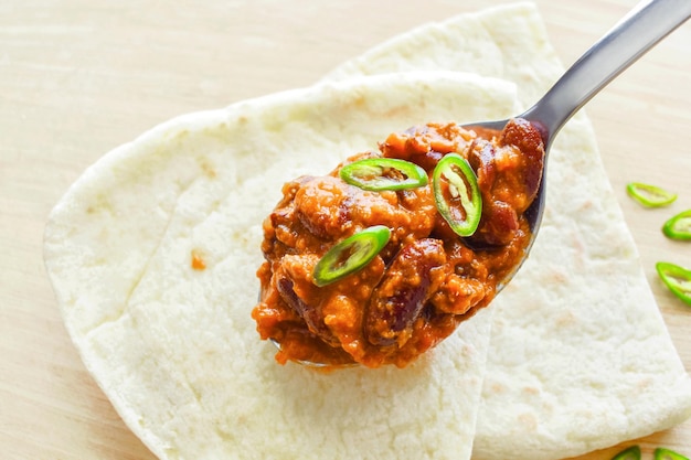 Chilli con carne al cucchiaio con pane naan su una tavola da taglio