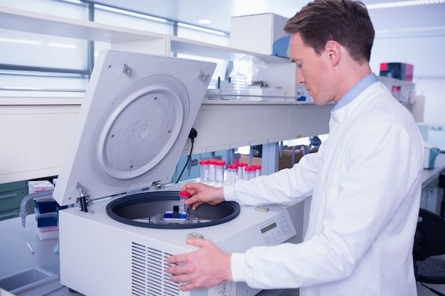 Chimico in camice da laboratorio usando una centrifuga