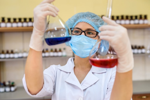 Chimico in laboratorio guardando il pallone con sostanza liquida