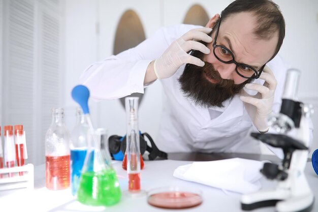 Chimico pazzo. Uno scienziato pazzo conduce esperimenti in un laboratorio scientifico. Esegue la ricerca utilizzando un microscopio.