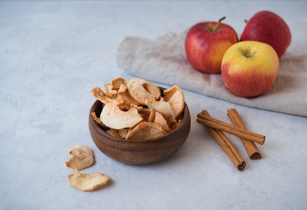 Chip di mela casalinghi dolci al forno con cannella in ciotola di legno su fondo grigio