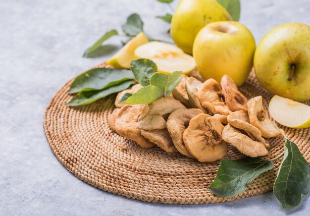 Chip di mele essiccate e mele fresche verdi su un tavolo bianco