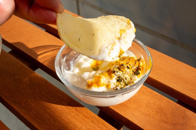 Chip di patate con verdure e tuffo in ciotola sul tavolo del ristorante di legno al sole