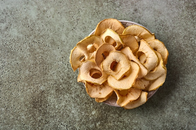 Chip disidratati di mele sul piatto sullo spazio della copia di vista superiore del fondo di legno strutturato