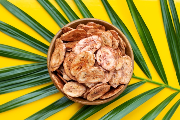 Chips di banana su foglie verdi con superficie gialla