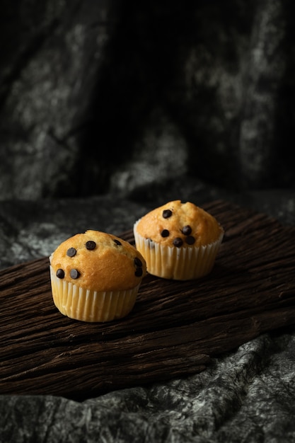 Chips di cioccolato del muffin sul forno di legno di tono scuro del fondo