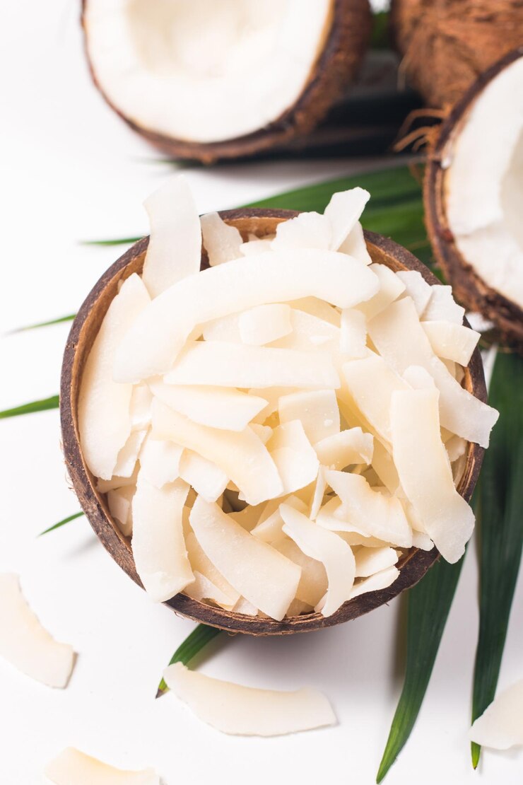 Chips di cocco con cocco e foglie verdi su sfondo bianco. Concetto isolato.