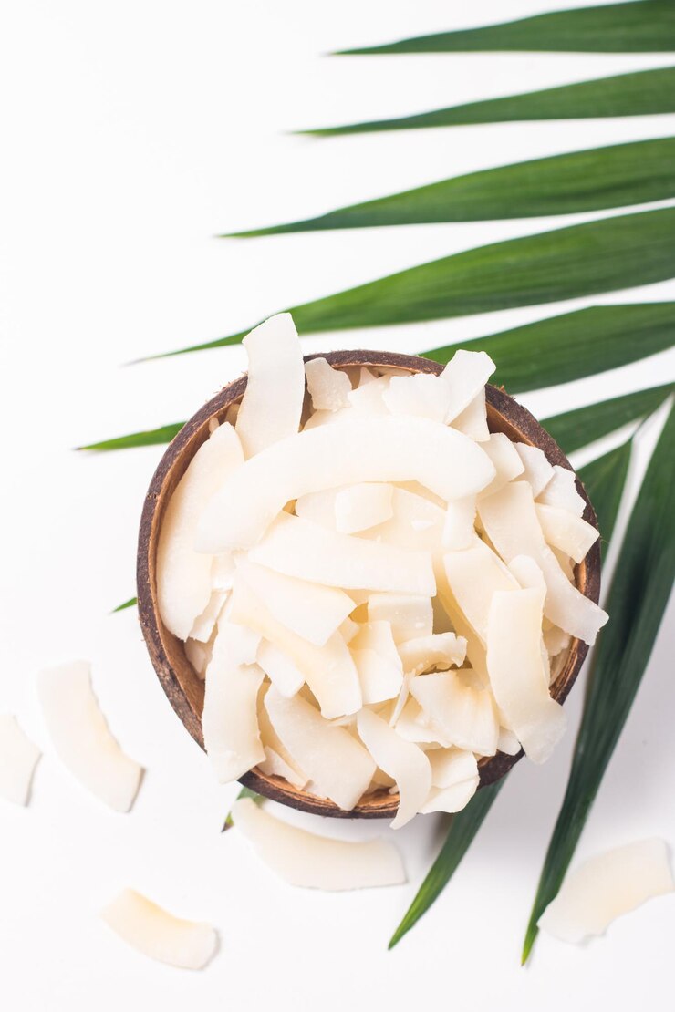 Chips di cocco con cocco e foglie verdi su sfondo bianco. Concetto isolato.