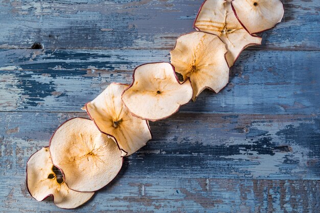 Chips di mela secca su legno blu con spazio di copia.