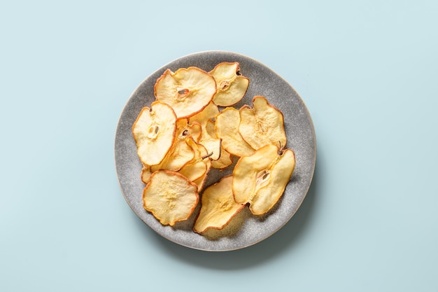 Chips di pera di frutta su sfondo blu dessert vegano senza zucchero vista dall'alto