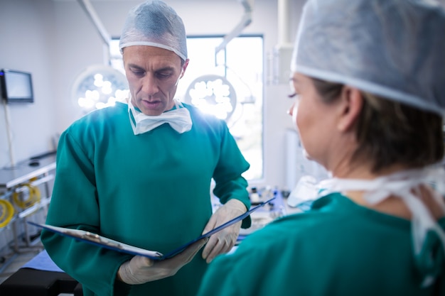 Chirurghi che discutono sopra i rapporti medici nella sala operatoria