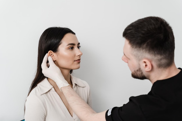 Chirurgia dell'orecchio di otoplastica Il medico chirurgo esamina le orecchie della ragazza prima della chirurgia estetica di otoplastica Rimodellamento chirurgico del padiglione auricolare e dell'orecchio