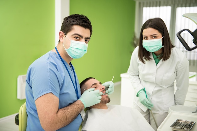 Chirurgia presso l'ufficio del dentista Il medico sta lavorando sulla bocca del paziente con l'aiuto di un assistente