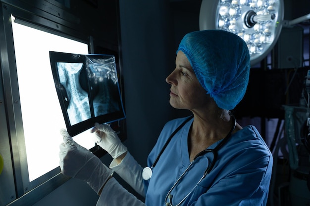 Chirurgo che esamina i raggi X su una scatola luminosa nella sala operatoria di un ospedale