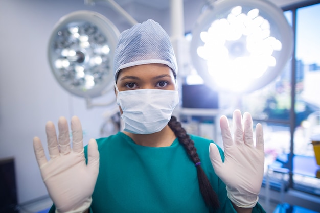 Chirurgo che indossa il teatro in funzione dei guanti chirurgici
