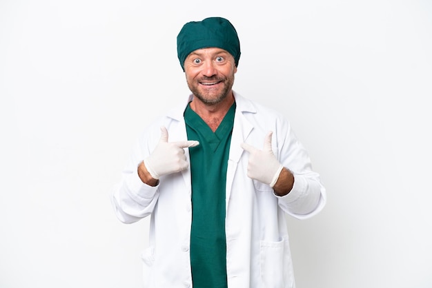 Chirurgo di mezza età in uniforme verde isolato su sfondo bianco con espressione facciale a sorpresa