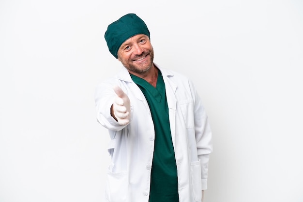 Chirurgo di mezza età in uniforme verde isolato su sfondo bianco stringe la mano per chiudere un buon affare