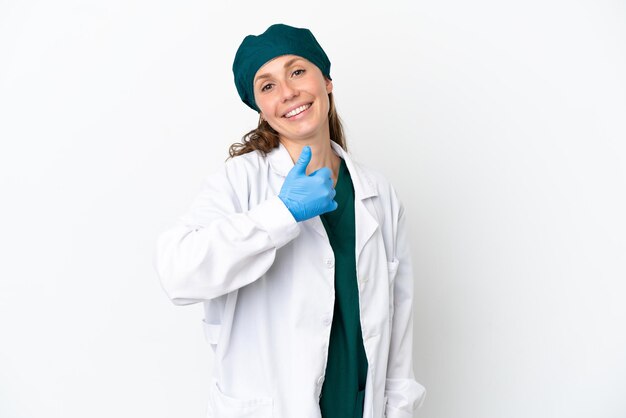Chirurgo donna caucasica in uniforme verde isolata su sfondo bianco che dà un pollice in alto gesto