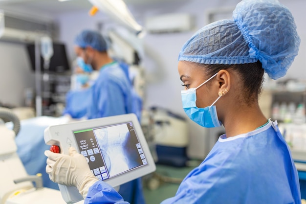 Chirurgo donna con maschera chirurgica in sala operatoria utilizzando una macchina chirurgica guidata da immagini 3D