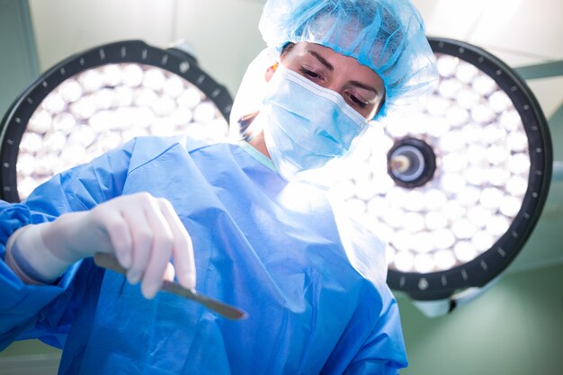 Chirurgo femminile che tiene attrezzatura medica nella sala operatoria